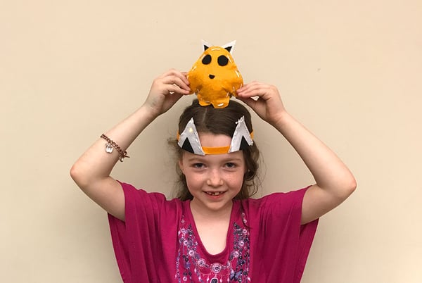 Camper wears an e-textile headband and holds a plush project above her