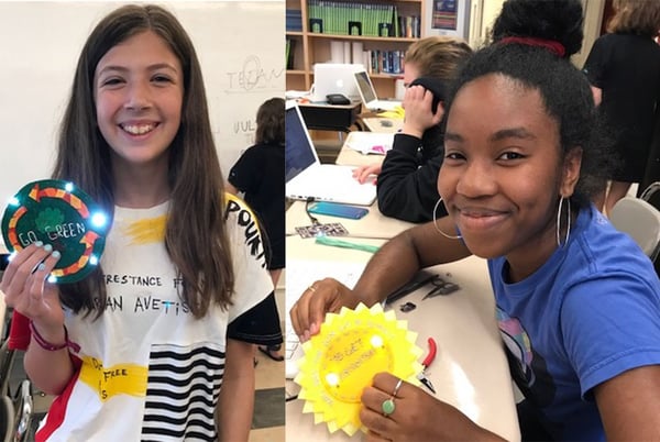 Two students holding light up e-textile badges they created.